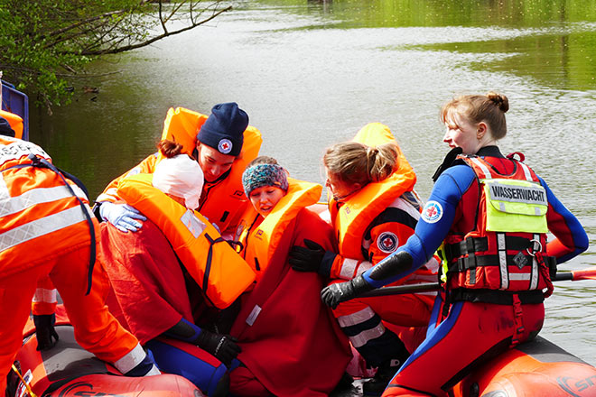 Man sieht ein Schlauchboot auf dem Wasser, im Schlauchboot befinden sich Wasserretter und Mimen, die ein Rettungsszenario im Rahmen der Landesmeisterschaft durchführen.