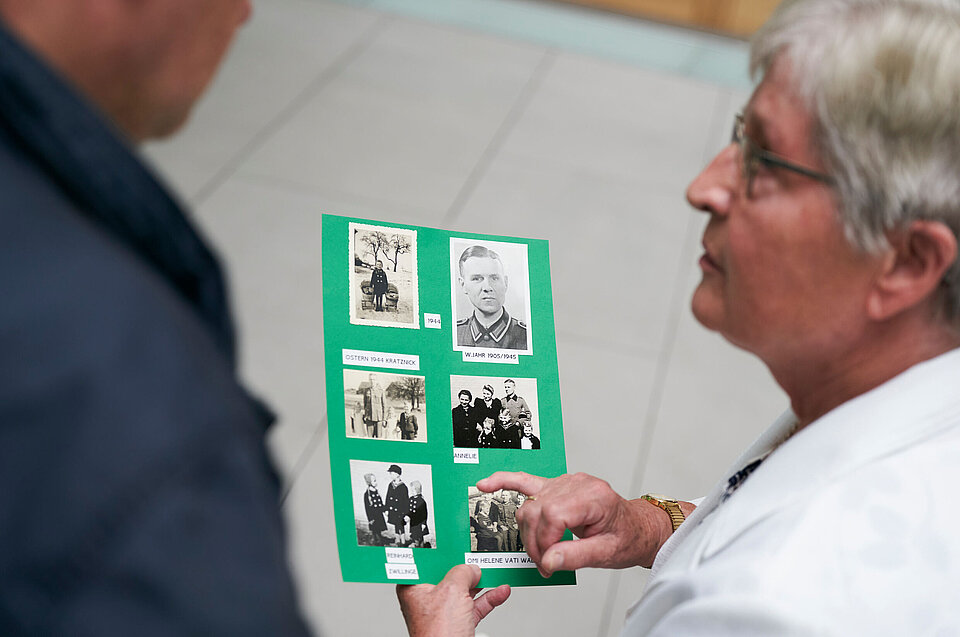 Person zeigt auf eine grüne Karte mit Vermisstenbildern