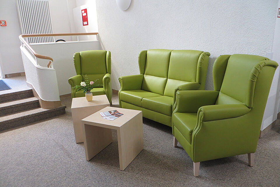 Sitzgruppe im Foyer aus grünen Sesseln und einem 2-sitzigen Sofa